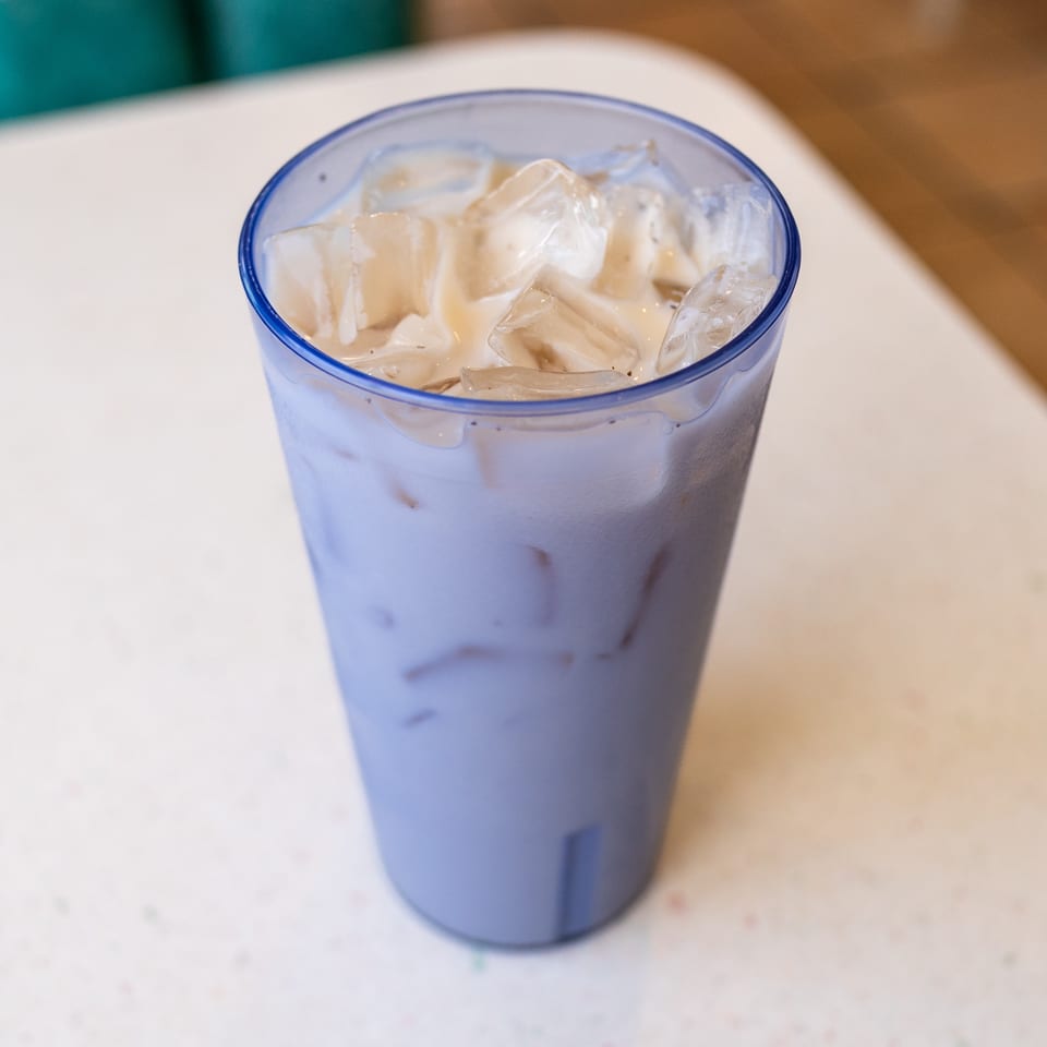 Blue-rimmed glass filled with an iced creamy beverage on a white restaurant table.